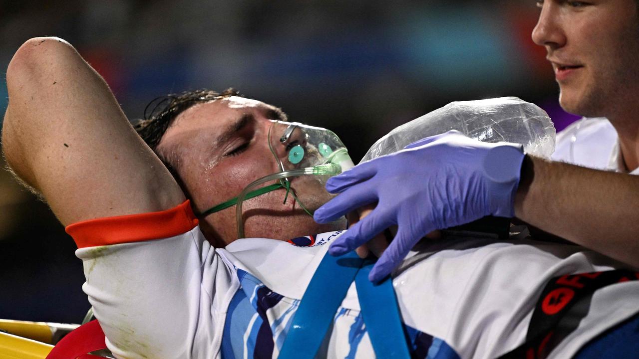 A medical official assists Namibia's inside centre Le Roux Malan (L) as he is moved from the pitch. (Photo by Lionel BONAVENTURE / AFP)