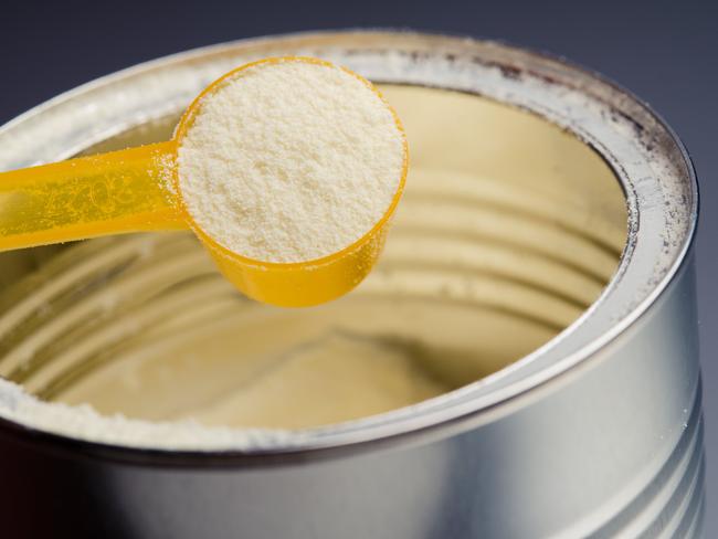 spoon with infant formula on background