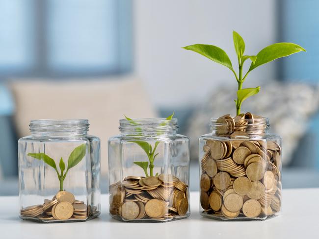 Green plant growing in glass jar with coins, superannuation generic