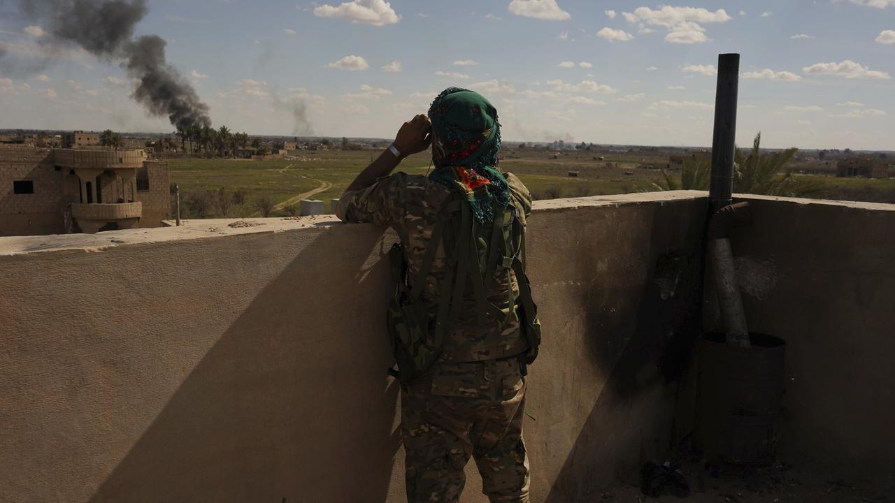 A U.S.-backed SDF fighter watches black smoke billow from the last small piece of territory held by Islamic State militants. Picture: AP Photo/Andrea Rosa