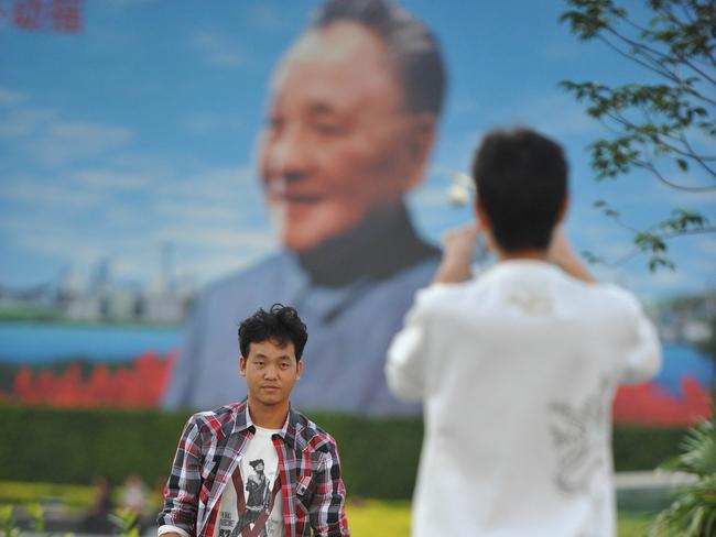 Two men takes photos in front of a giant poster of former Chinese leader Deng Xiaoping, the man who led China towards a market economy, in Shenzhen, located in the southern province of Guangdong, China, 29/11/2011. Thousands of workers in factories in Guangdong have gone on strike in recent days, protesting over low salaries, wage cuts or tough conditions, and triggering a strong police response and some clashes.