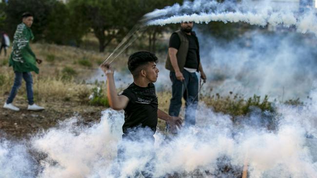 A Palestinian slings back an Israeli teargas canister during a protest in Ramallah on Wednesday. Picture: AFP