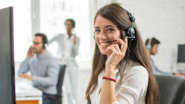 Young friendly operator woman agent with headsets working in a call centre.