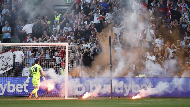 Melbourne Victory’s Paul Izzo removes a flare thrown by fans from the pitch. Picture: Darrian Traynor/Getty Images