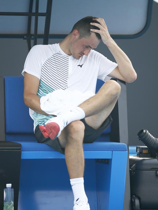 Tomic wraps his injured right hand in a towel.