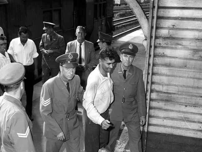 Police escort Michael Fomenko at the Mayne Junction railway station in 1964.