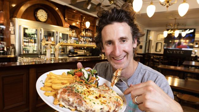 Coopers Alehouse general manager Nick Sando holding one their schnitzels that cost an average $28, but are $12 on Thursdays. Picture: Kelly Barnes