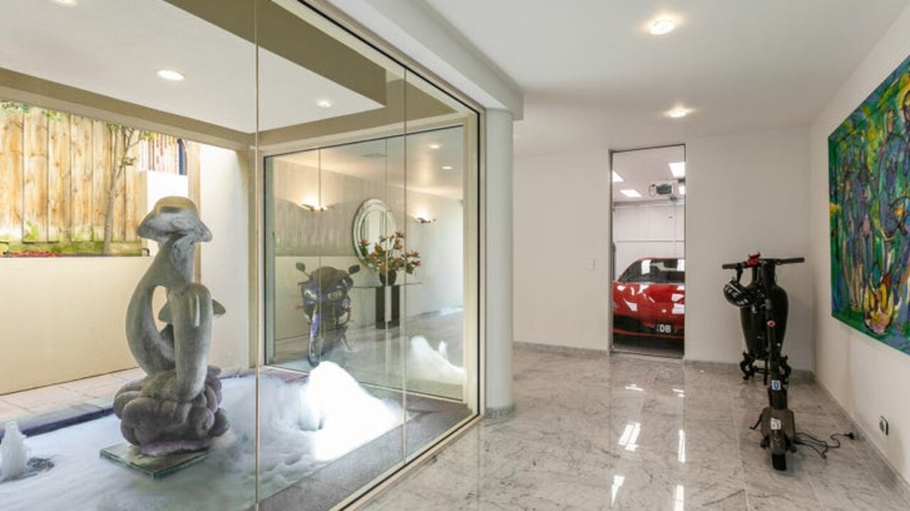 An indoor pond and sculpture stand near the five-car garage which provides direct access to the house.