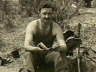 Korea, c. 1950-10. Wearing a singlet, 2/949 Corporal G.F. ('Fibber') McGee, a member of the Machine Gun Platoon, 3rd Battalion, The Royal Australian Regiment (3RAR), sits on the edge of a narrow slit trench or dugout and reads a book. Lying on the ground beside him (left) are a trenching tool, some ration boxes, a mug and a billy, while on the other side are some pouches, a slouch hat, a dixie and a pair of binoculars hanging from the barrel of his .303 rifle which is standing in the trench. At rear, some other soldiers are taking food out of ration boxes.   Picture: Australian War Memorial