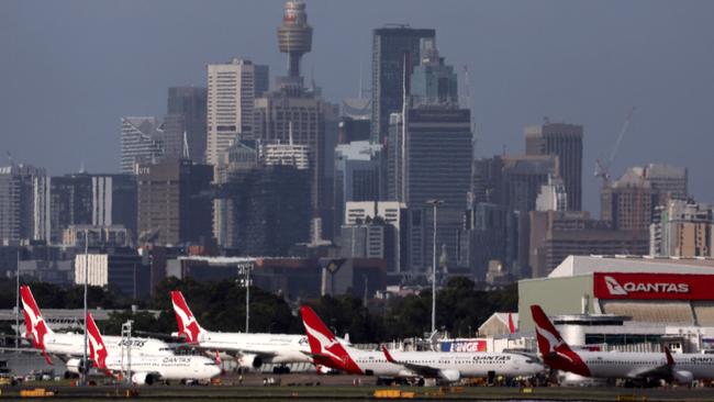 This picture taken on December 6, 2023 shows the Sydney central business district (CBD) behind Qantas Airways passenger aircraft parked at the Sydney domestic airport. (Photo by DAVID GRAY / AFP)