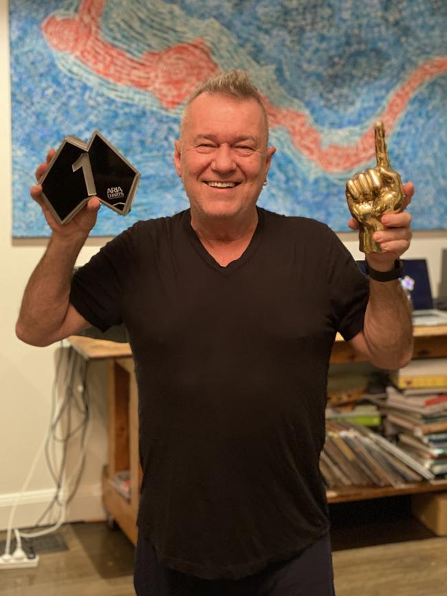 Jimmy Barnes at his home on Friday, with the ARIA statue denoting his 13th No 1 album and a golden statue modelled on Gudinski's famous raised index finger. Picture: Eliza-Jane Barnes