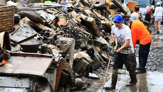 Volunteers work to clear rubbish and mud left by floodwaters in the Brisbane suburb of St Lucia. Picture: Craig Greenhill