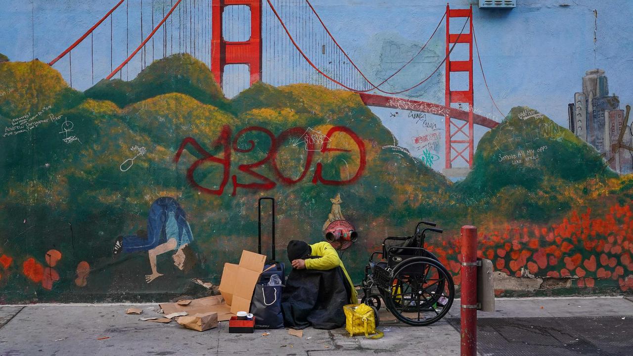 A homeless person lies against a mural of the Golden Gate Bridge near APEC Summit headquarters on November 11, 2023 in downtown San Francisco, California. Picture: Loren Elliott / AFP