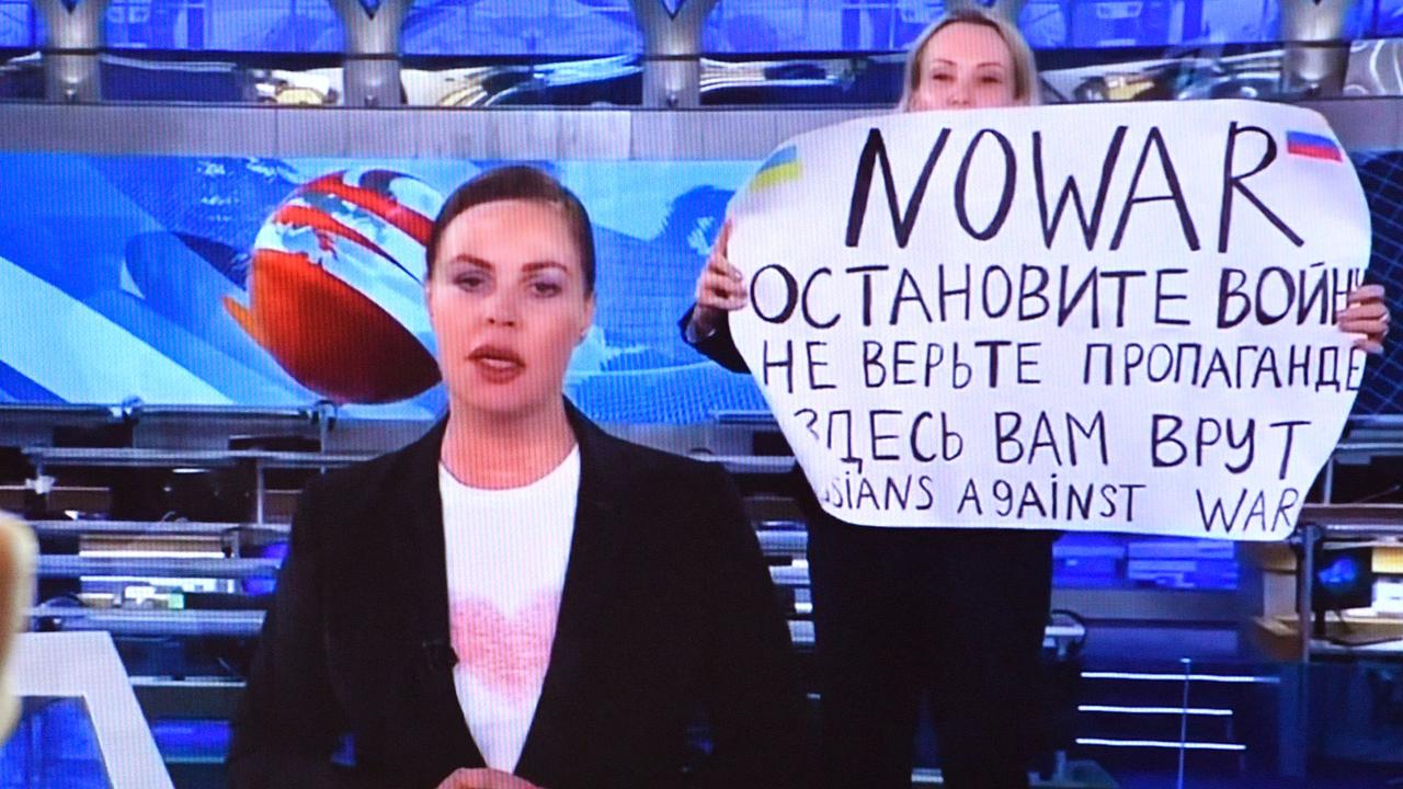 Marina Ovsyannikova entering an on-air TV studio during Russia's most-watched evening news broadcast, holding up a poster which reads as "No War".