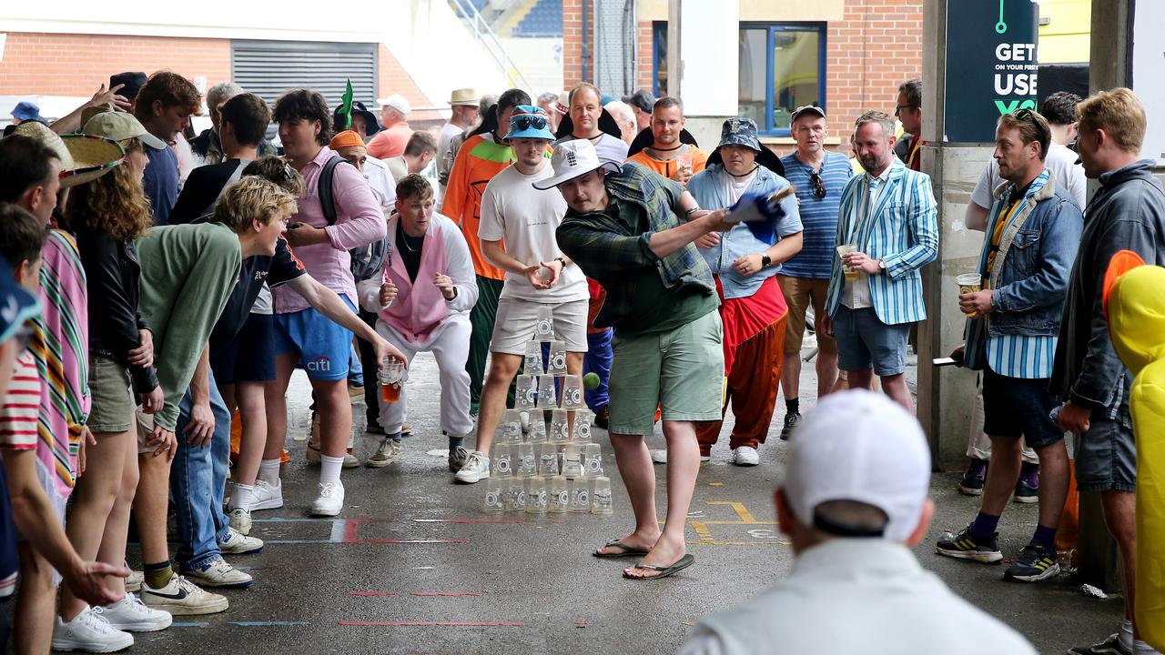 Spectators make the most of the rain delay with a spot of cricket, with empty pints for stumps. Picture: Getty