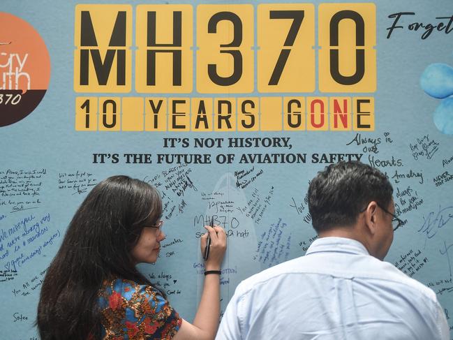 TOPSHOT - A woman writes a message during an event held by relatives of the passengers and supporters to mark the 10th year since the Malaysia Airlines flight MH370 carrying 239 people disappeared from radar screens on March 8, 2014 while en route from Kuala Lumpur to Beijing, in Subang Jaya on March 3, 2024. (Photo by Arif Kartono / AFP)