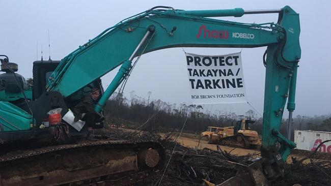 Protester and signage with mining equipment at the Riley Mine. PICTURE: Bob Brown Foundation