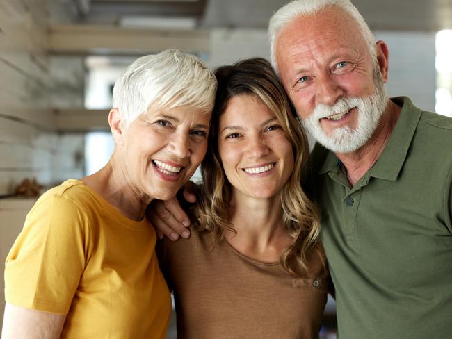 Happy adult daughter enjoying with her mature parents at home and looking at camera; Bank of Mum and Dad generic money