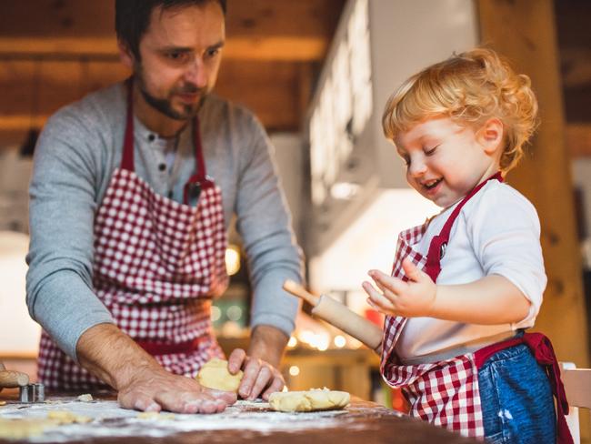 SUNDAY TELEGRAPH SPECIAL. BACKYARD ACADEMY. Man and toddler boy making cookies at home. Father and son baking gingerbread Christmas cookies.