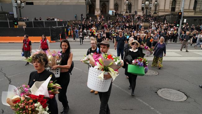 People walk to ride the 86 tram with flowers for Aiia Maasarwe. Picture: AAP/Stefan Postles