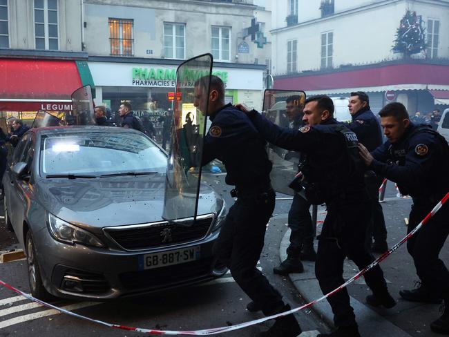 TOPSHOT - French riot police officers run to disperse protestors during a clash following a statement by French Interior Minister at the site where several shots were fired along rue d'Enghien in the 10th arrondissement, in Paris on December 23, 2022. - Three people were killed and three injured in a shooting in central Paris on December 23, 2022, police and prosecutors said, adding that the shooter, in his 60s, had been arrested. The motives of the gunman remain unclear, with two of the four injured left in a serious condition, the French officials said. (Photo by Thomas SAMSON / AFP)