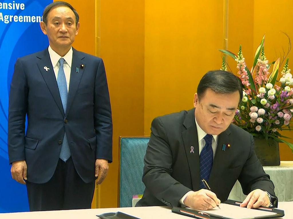 Japan's Minister of Economics, Trade and Industry Hiroshi Kajiyama signs the agreement. Picture: Vietnam Host Broadcaster / AFP