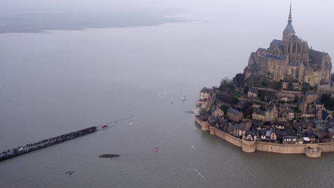 An aerial view as a high tide submerges a narrow causeway leading to the Mont Saint-Michel, on France's northern coast. Pic: AP.