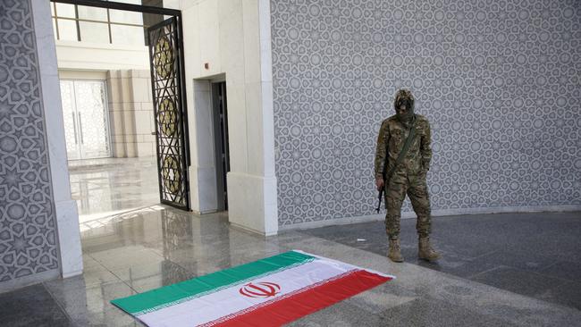 An armed man poses beside an Iranian flag inside the Presidential Palace. Picture: Getty Images