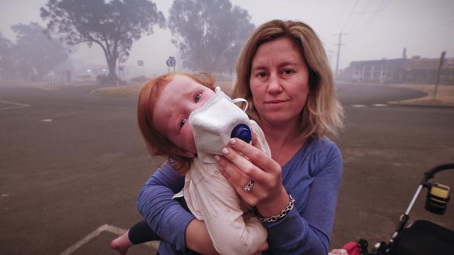 Laura Langmead shields daughter Evie’s face to help filter the smoke from Mallacoota’s bushfires. Picture: David Caird