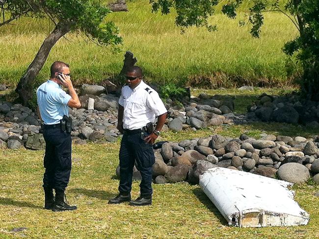 A policeman and a gendarme standing next to a piece of debris later identified from missing Malaysia Airlines plane MH370, found on the French Indian Ocean island of La Reunion. Picture: AFP