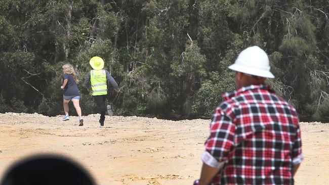 Black Swan Lake protest at Bundall goes to another level, with protesters chaining themselves to the fence and then getting themselves arrested after running onto the worksite and stopping the trucks. Security chases a protester. Picture Glenn Hampson