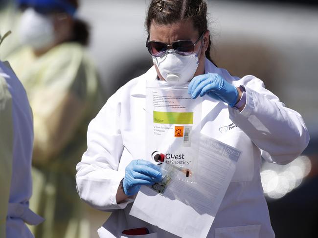 A medical technician carries a plastic envelope containing a vial with a swab used for a test. Picture: AP