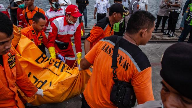 Search and Rescue personnel carry a body bag containing remains of a passenger. Picture: Getty