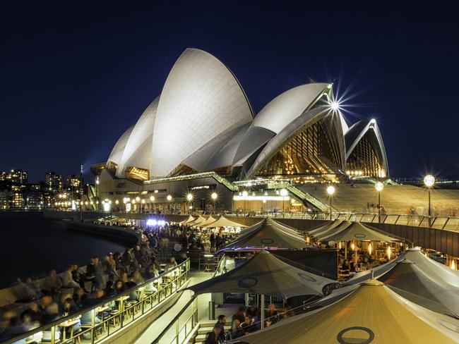 Sydney, Australia - August 6, 2017: A busy evening around Sydney Harbour, New South Wales, and people inhabit the numerous bars and restaurants found in the pedestrianised area next to Circular Quay. In the distance we see the illuminated roofline of the city's iconic Opera House.  Picture: istock