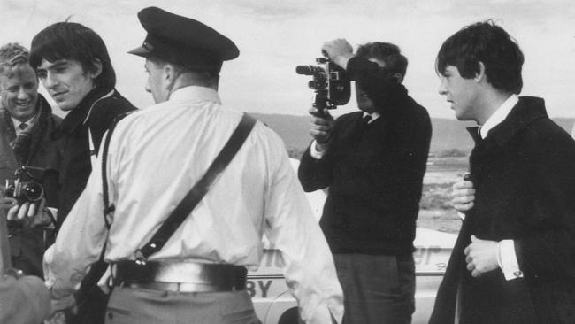 Former Advertiser journalist Jonathon Stone, far left behind George Harrison, covering The Beatles' arrival at Adelaide Airport on June 12, 1964, with Paul McCartney, right. Picture: Advertiser staff photographer.