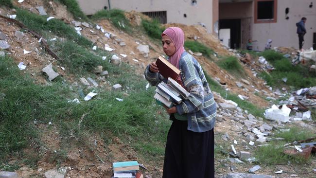 A displaced Palestinian collects books, from the destroyed Islamic University to use as fuel to cook food, in Gaza City on March 21, 2025. Picture: AFP