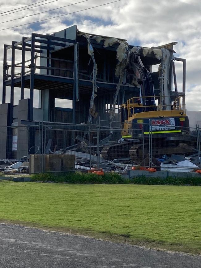 A digger tears through the front of the unfinished house at 9 Gold Coast Drive, Carrickalinga.