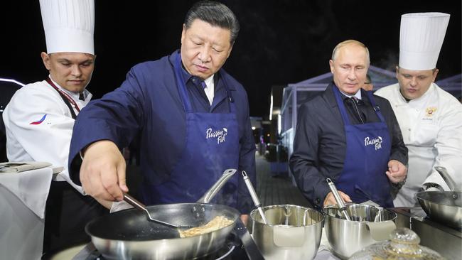 Chinese President Xi Jinping and Russian President Vladimir Putin flip pancakes at an exhibition linked to the Eastern Economic Forum in Vladivostok. Picture: AP