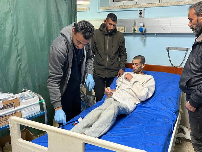 A Palestinian prisoner speaks with doctors at the European Hospital in Khan Yunis in the southern Gaza Strip early on February 27, 2025, following his release by Israeli authorities. Hamas handed over the coffins of four hostages early on February 27, Israeli authorities confirmed, followed soon after by the return of hundreds of freed Palestinian prisoners to the West Bank and Gaza. In the West Bank and Gaza, AFP journalists saw hundreds of Palestinian prisoners freed by Israel arrive on buses accompanied by Red Cross vehicles. More than 600 were due to be released in the latest exchange, while Al Jazeera reported nearly 100 would be deported to Egypt. (Photo by AFP)