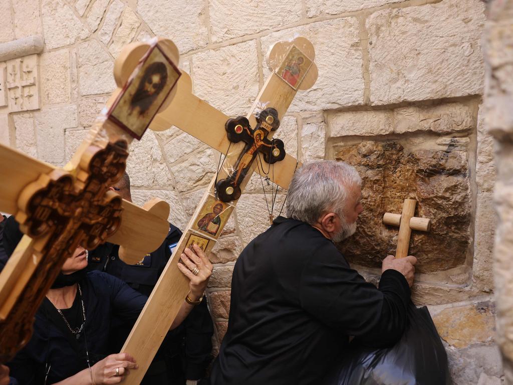 An Orthodox Christian worshipper touches a station along the Via Dolorosa in Jerusalem's Old City with a cross during the Orthodox Good Friday procession. Thousands of Christian pilgrims take part in processions along the route where, according to tradition, Jesus Christ carried the cross during his last days. Picture: Ahmad Gharabli/AFP