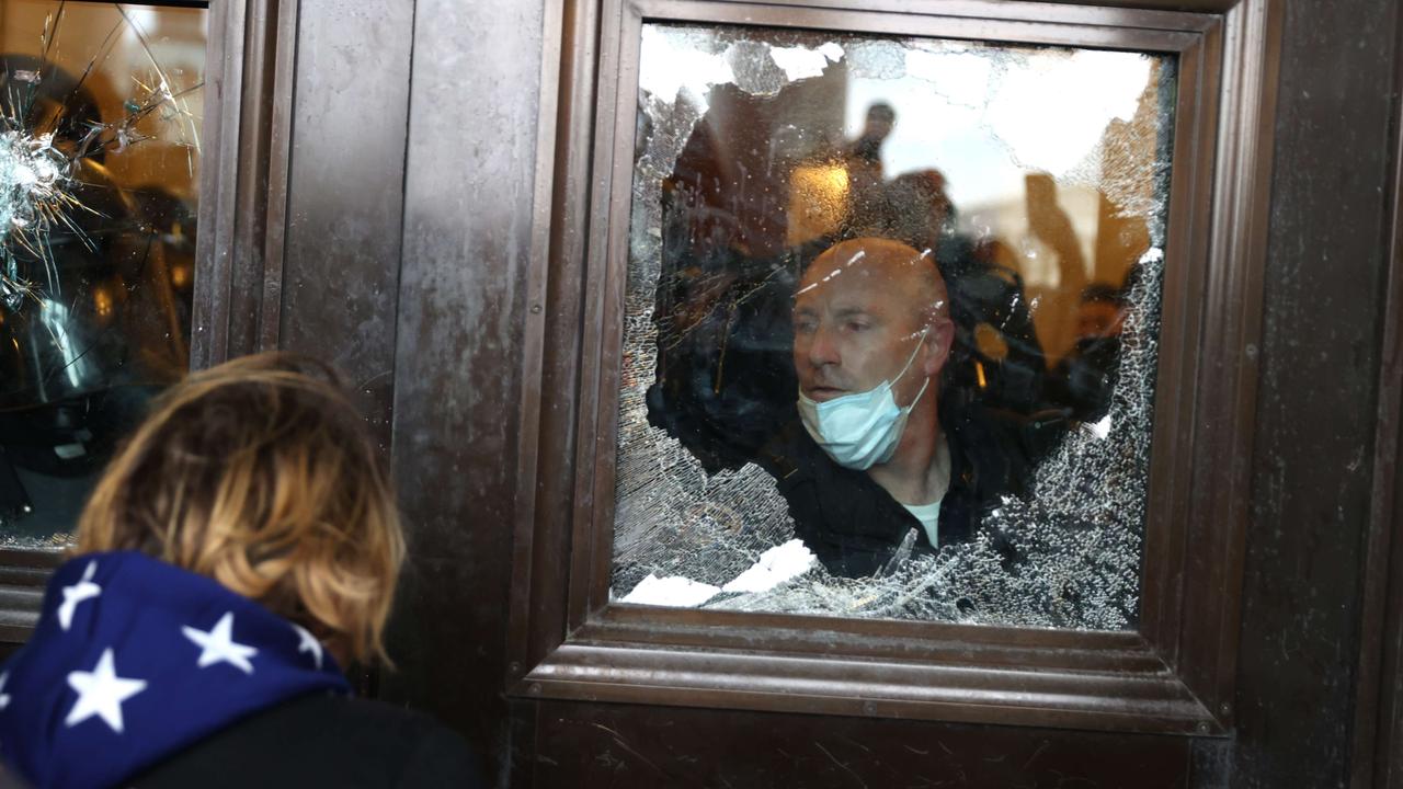 A police officer looks out of a broken window as protesters gather on the US Capitol Building. Picture: Tasos Katopodis/Getty Images/AFP