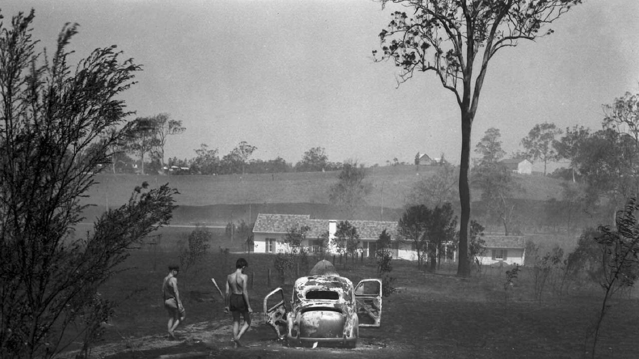 A burnt-out car lies in the wake of a bush and grass fire at Kenmore in 1951 when the area was still mostly rural. Picture: Bob Millar