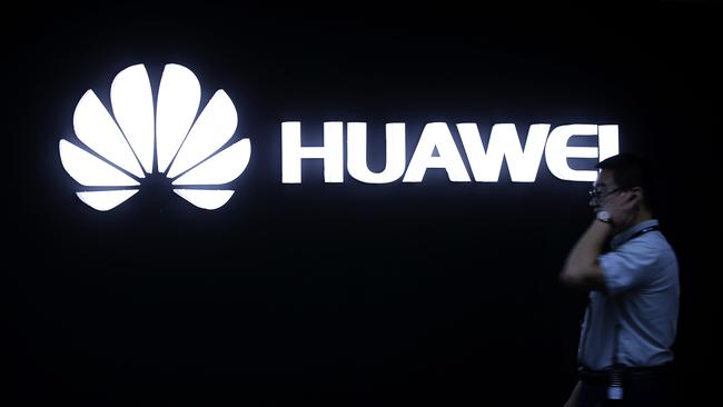 A man walks past a Huawei logo during a launch event for the Huawei Matebook in Beijing. (AP Photo/Mark Schiefelbein)