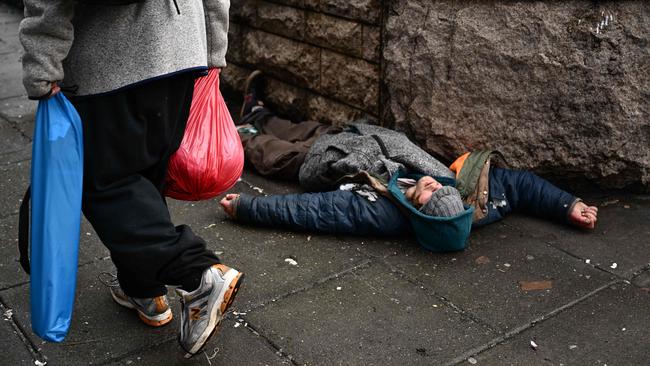 A person lays on the street in downtown Portland, Oregon where hard drugs were decriminalised three years ago. Now there are no arrests, just a fine and a card with a telephone number where the user can get help. (Picture: Patrick T. Fallon/AFP)