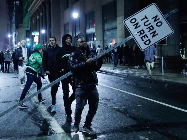 A man carries a traffic signal as Philadelphia Eagles fans celebrate.