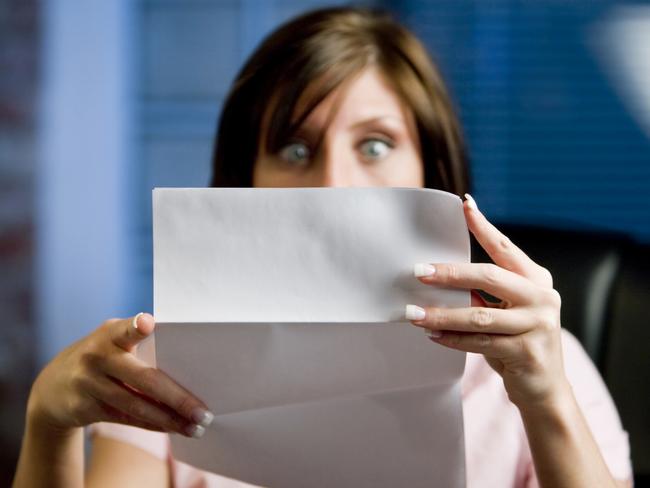 A woman looking at her mail (letter or bills)  in disbelief, shock!