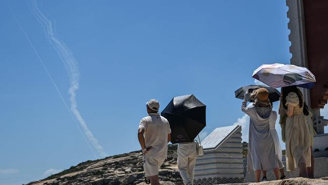 Smoke trails from projectiles launched by the Chinese military are seen in the sky as tourists look on from Pingtan Island, one of mainland China's closest point from Taiwan. Picture: AFP