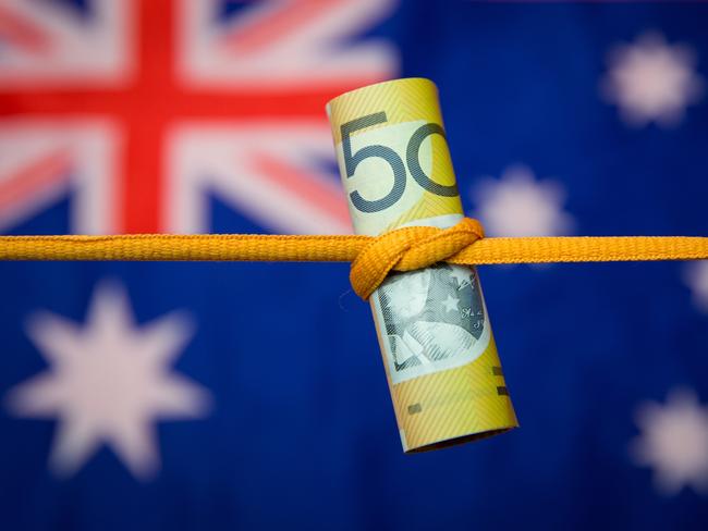 Studio shot close up of an Australian dollar note tied in a knot with the Australian flag as a background. Mortgage home loan money stress generic