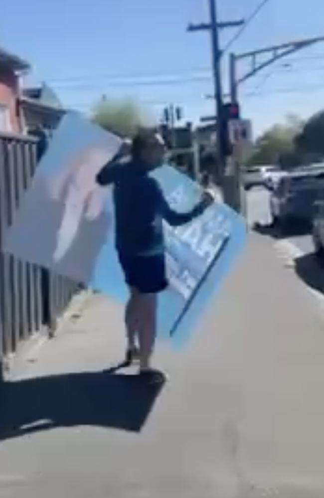 Peter Jordan makes off with a large Amelia Hamer poster in Kooyong. Picture: Supplied