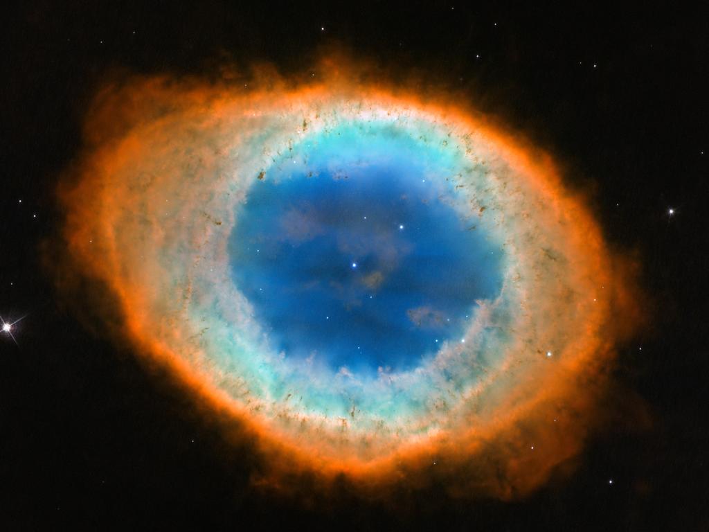 The dramatic shape and colour of the Ring Nebula, otherwise known as Messier 57. From Earth’s perspective, the nebula looks like a simple elliptical shape with a shaggy boundary. However, new observations combining existing ground-based data with new NASA/ESA Hubble Space Telescope data show that the nebula is shaped like a distorted doughnut.